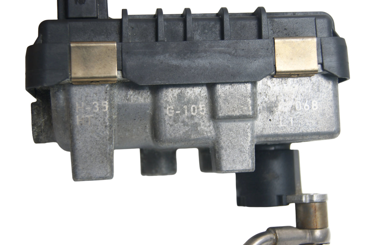 A used automotive part, specifically a metal and plastic engine control module with brass-colored clips and a black plastic cap, photographed on a white background.
