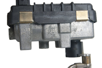 A used automotive part, specifically a metal and plastic engine control module with brass-colored clips and a black plastic cap, photographed on a white background.